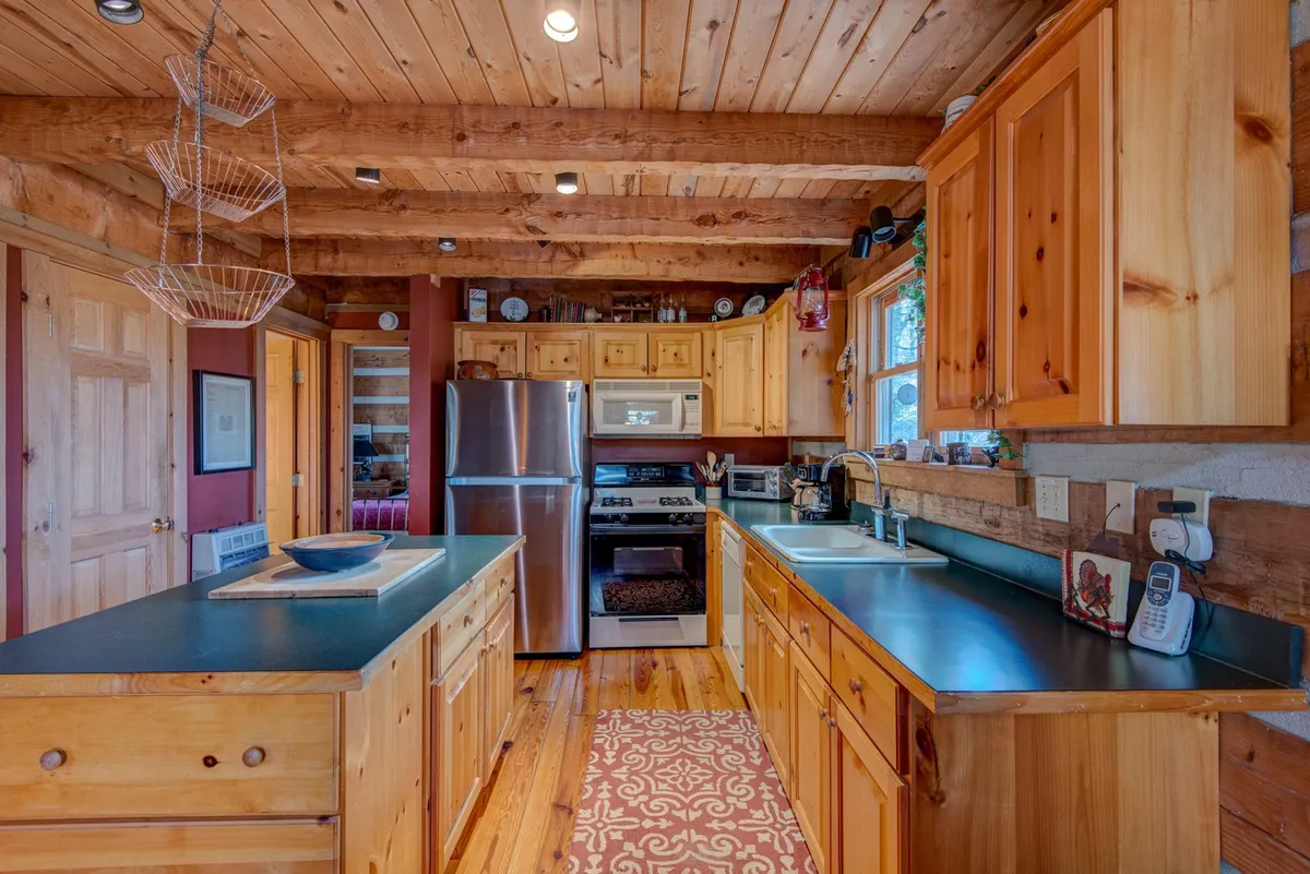 A bright, open kitchen with wooden cabinetry and stainless-steel appliances is shown, blending seamlessly into the open layout. The scene suggests an inviting place for cooking together, with enough space for family and friends to engage while meals are prepared.