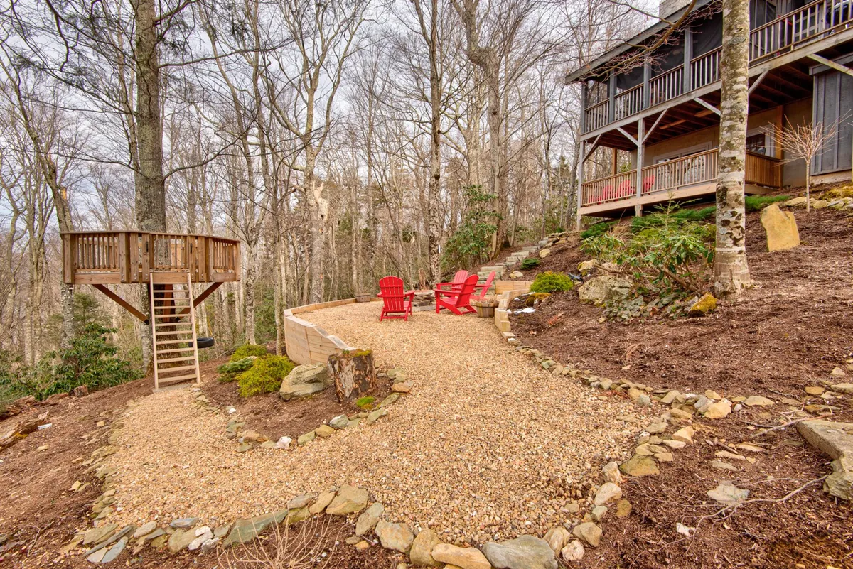 A serene outdoor scene featuring red Adirondack chairs, a wooden lookout tower, and a winding gravel path that suggests hidden corners to explore. The arrangement evokes both relaxation and the spirit of discovery.
